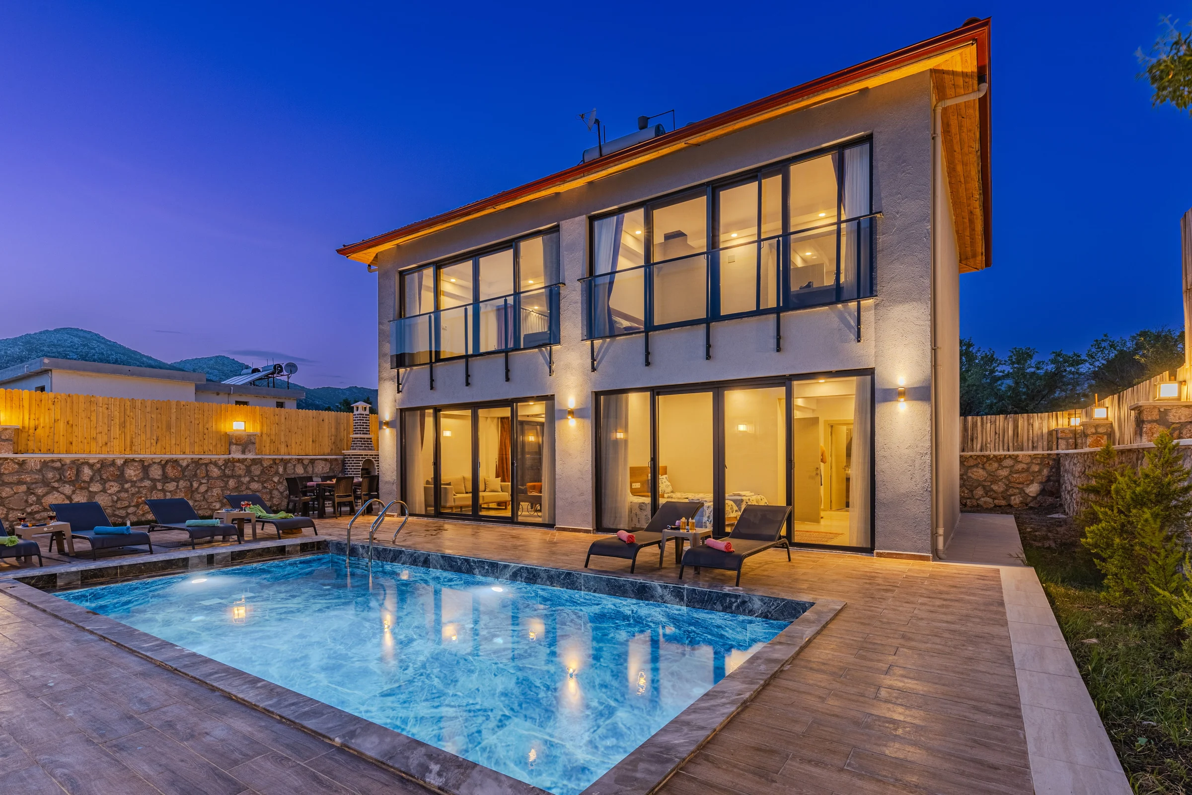 Two-storey house with a lit pool in the evening