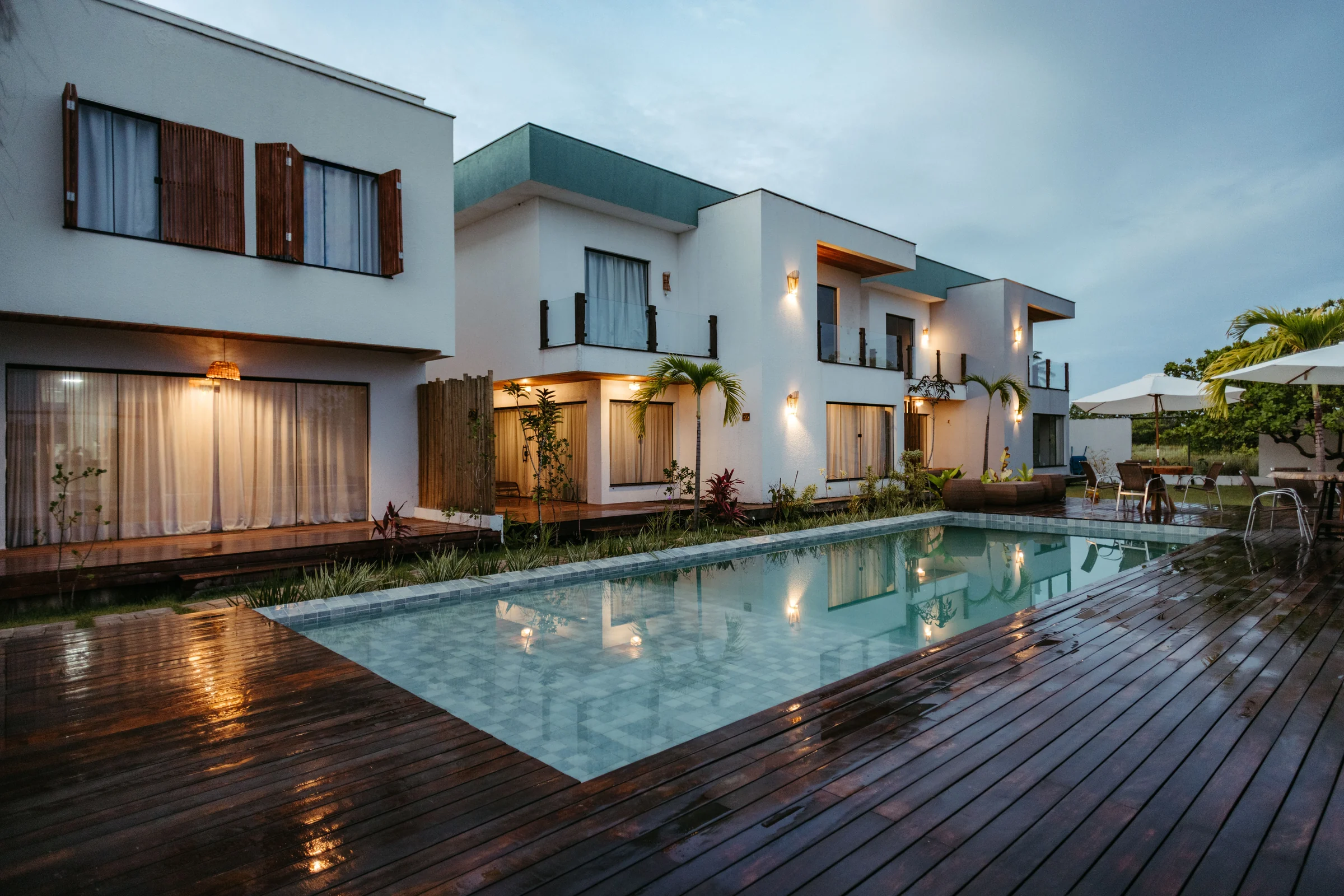 White residences beside a long pool at twilight